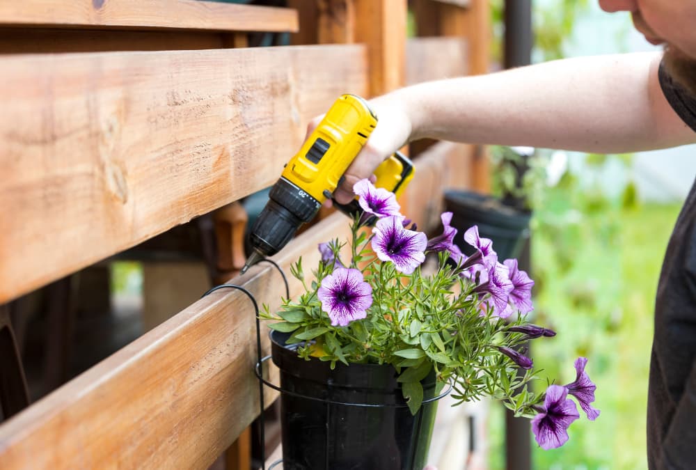 man drilling into garden fence